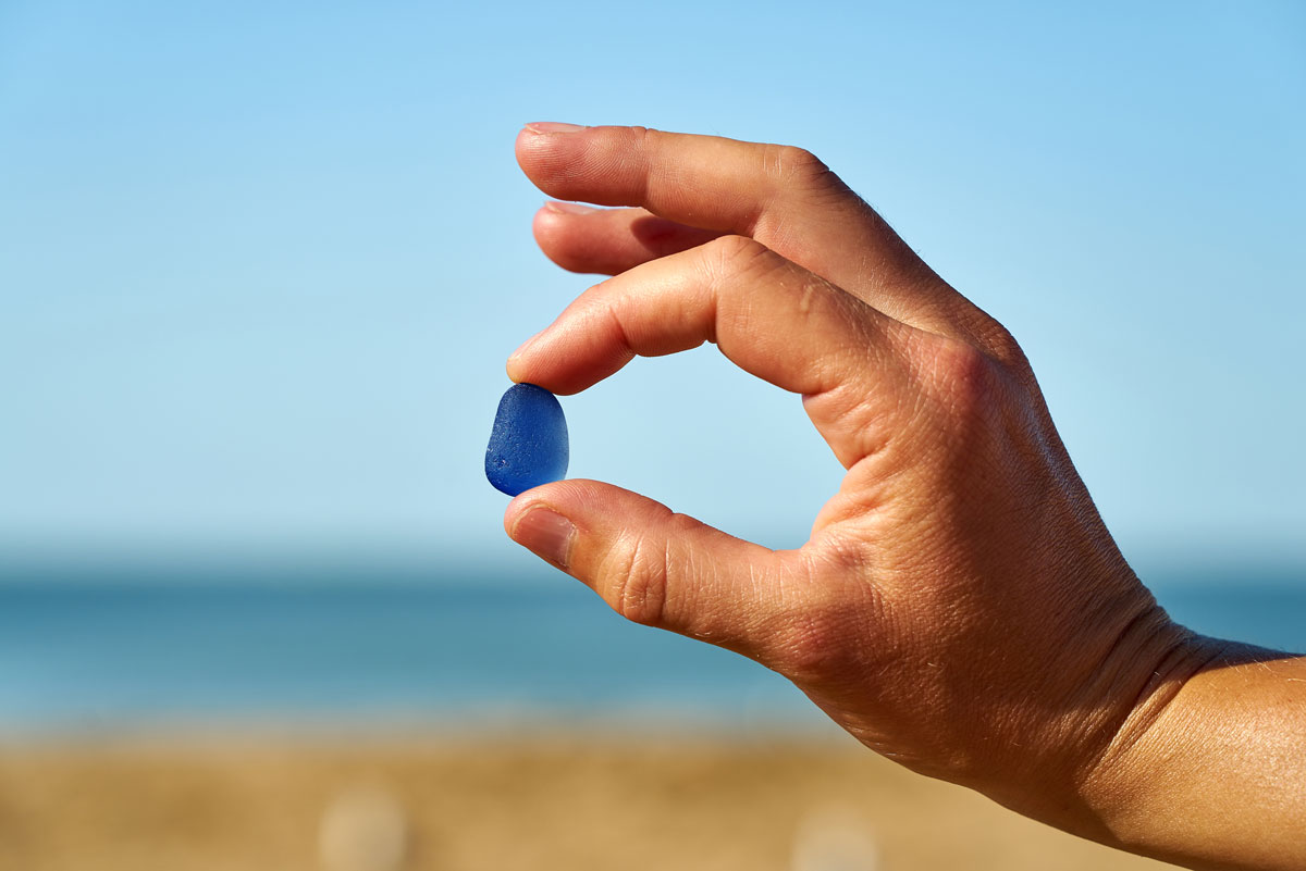 hand holidng a piece of blue sea glass