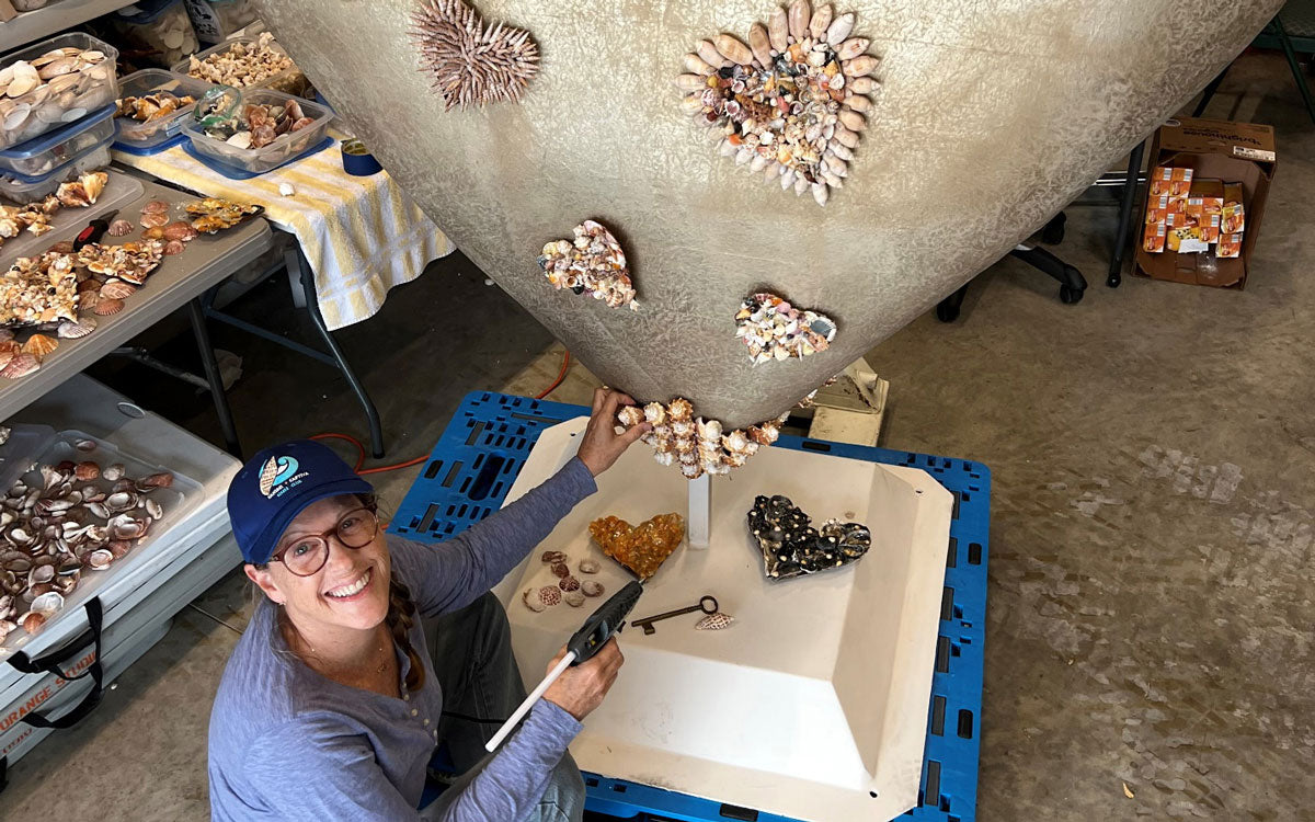 artist creating giant heart sculpture covered with sanibel seashells
