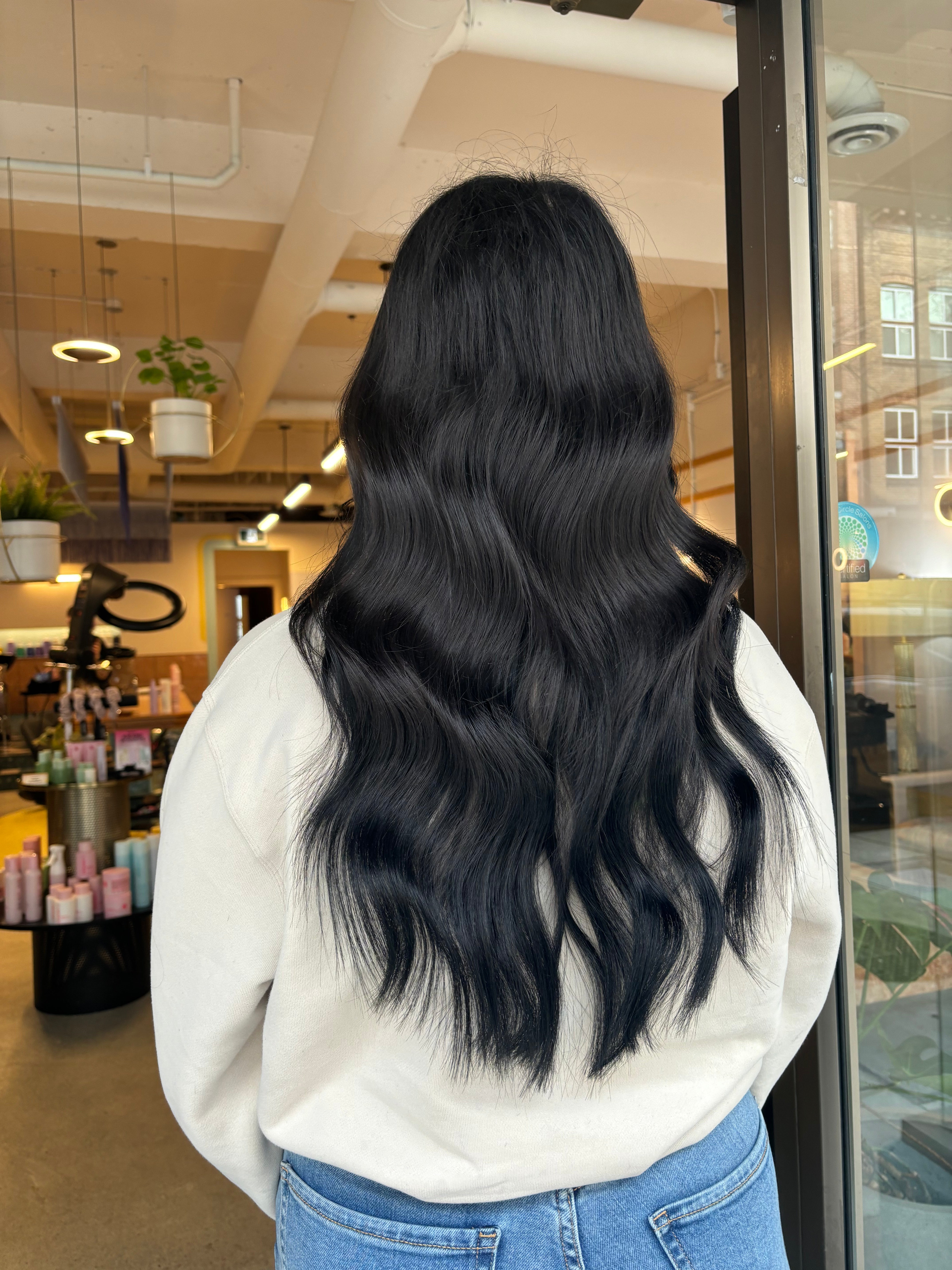 Smiling person with curly hair in front of a window with geometric designs.