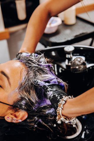 a woman's hair is being washed in a salon sink