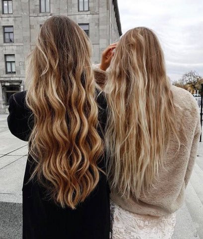 2 blonde girls standing beside each other, girl on the right has wavy hair, girl on the left has her hair curled