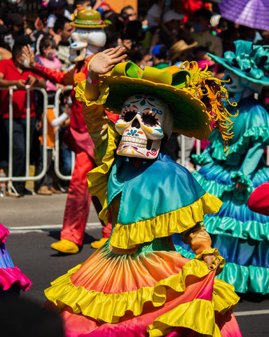 female skull wearing a festive dress and hat celebrating Day of the Dead