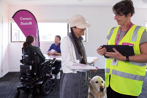 People at the census centre, one with a guide dog, and another in a powered wheelchair along with a helper in a high-vis vest
