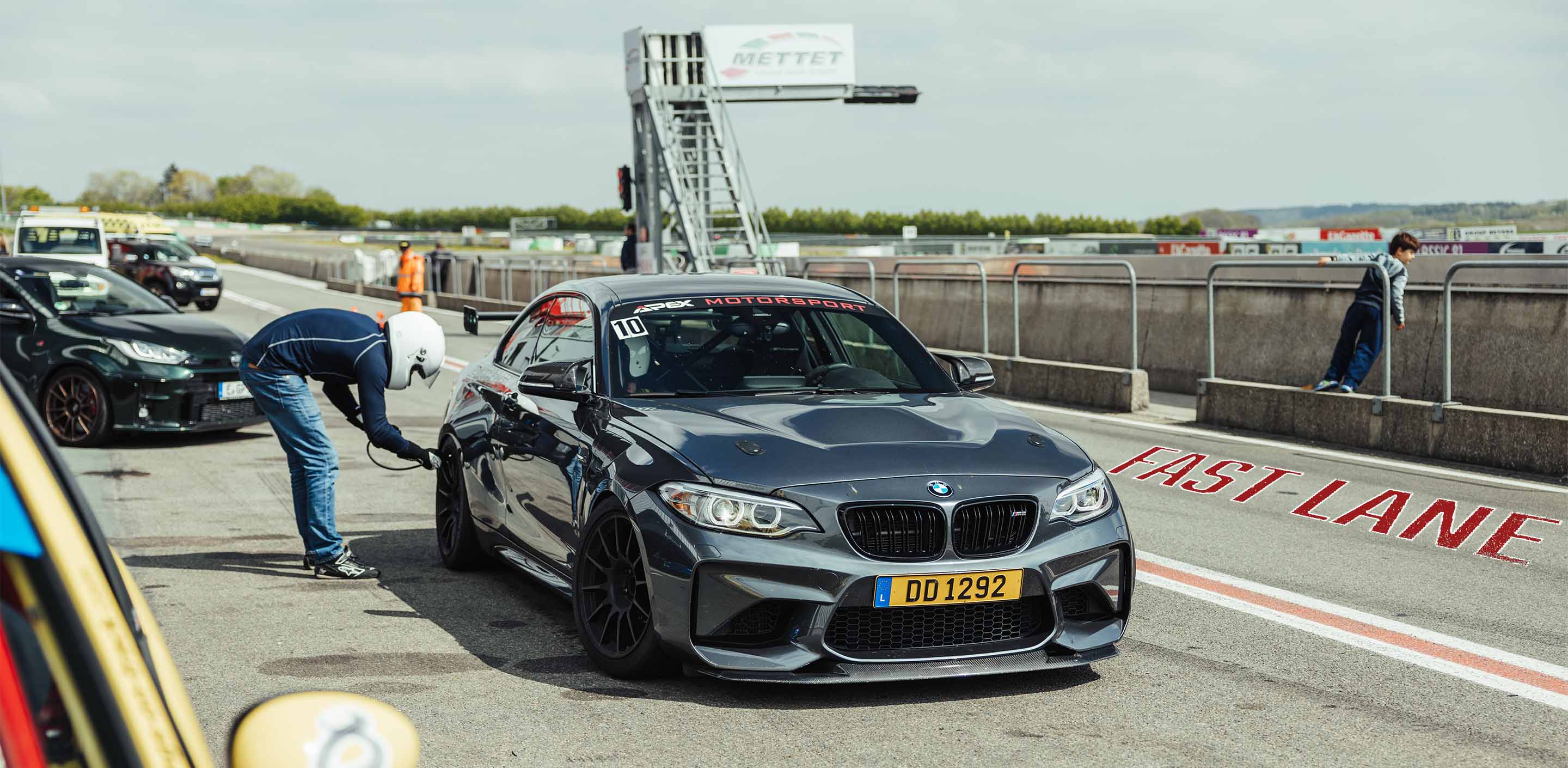 A driver of a BMW M2 checks his tyre pressure in the Pitlane at Circuit Mettet during a GP Days Open Pitlane Track Day