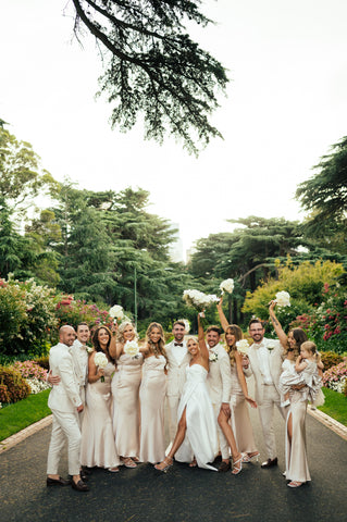 Bride and Groom with the bridal party. All throwing their arms in the air smiling