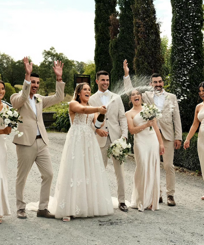 Bridal party popping chapmpagne and everyone laughing