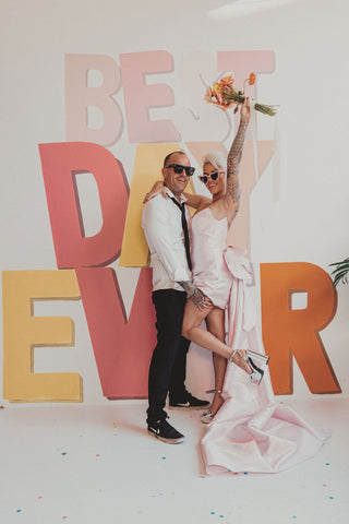 THE BEST DAY EVER SIGN WITH A BRIDE AND GROOM INFRONT