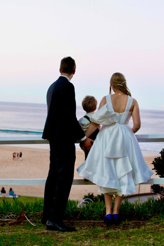 bride and groom with their son staring out at the ocean