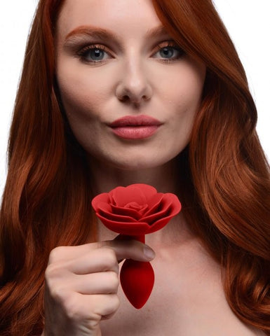 Femme rousse tenant un plug anal fleur silicone rouge entre les doigts-Le Royaume Du Plug