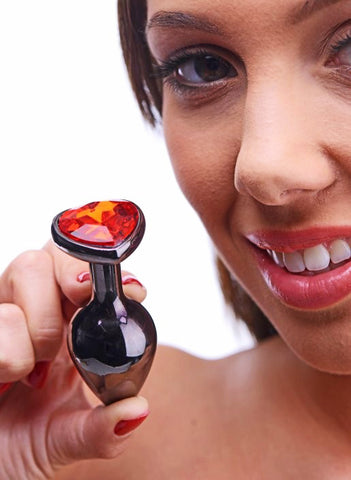Femme souriante tenant un plug anal diamant cœur rose rouge-Le Royaume Du Plug