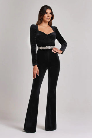 Woman wearing long-sleeved black jumpsuit with embellished belt and flared trousers