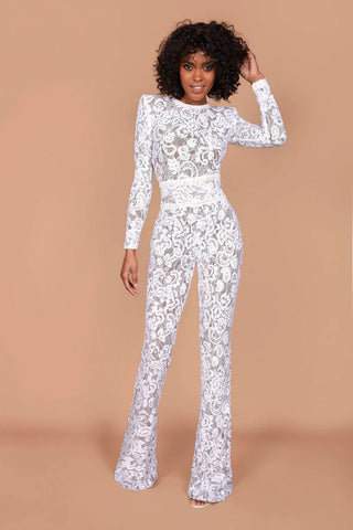 A woman wearing a white lace jumpsuit with dark nude lining