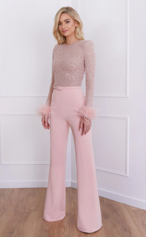 blonde woman stood wearing Amelia pink jumpsuit with feathered cuffs