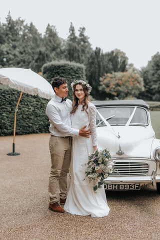 bride and groom hugging in front of a retro beetle car