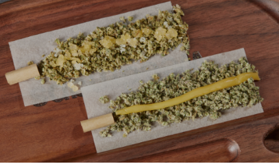 Joints that are being rolled with crushed weed. A thin layer of wax was laid out in the middle so that the heat from the cannabis can burn the oil to make this a very strong joint.