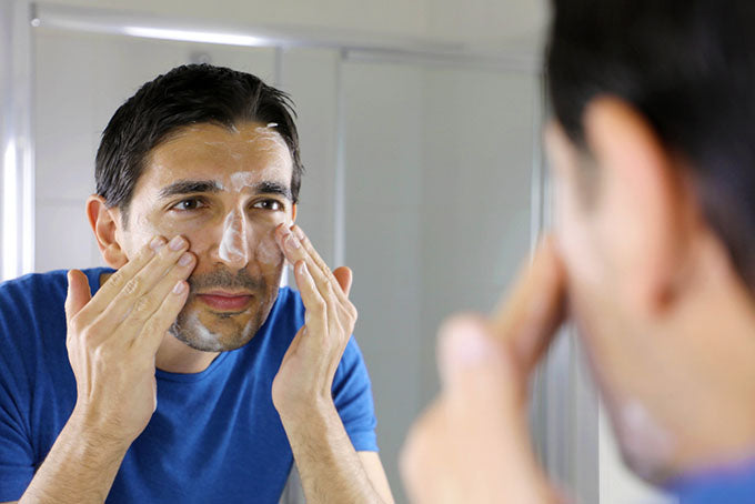 applying facial wash in mirror