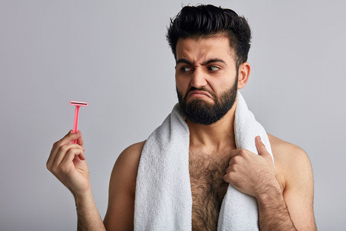 a man holding a razor and looking at it with disgust