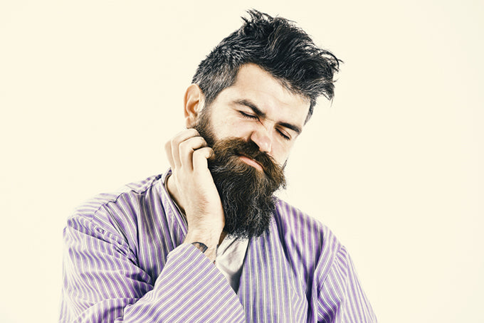 a man in pajamas itching his beard