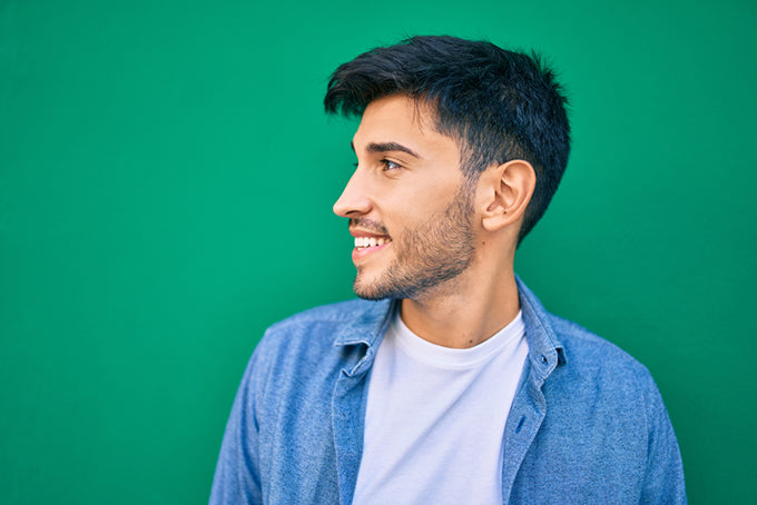 a profile shot of a smiling man against a green background