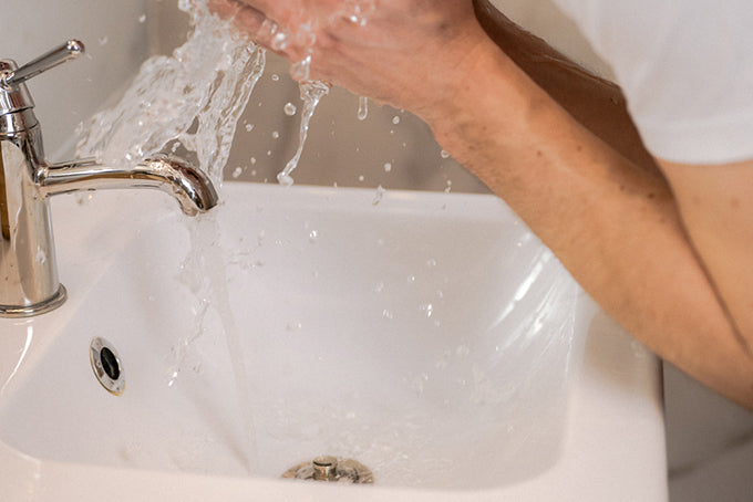 a man washing his face in a sink