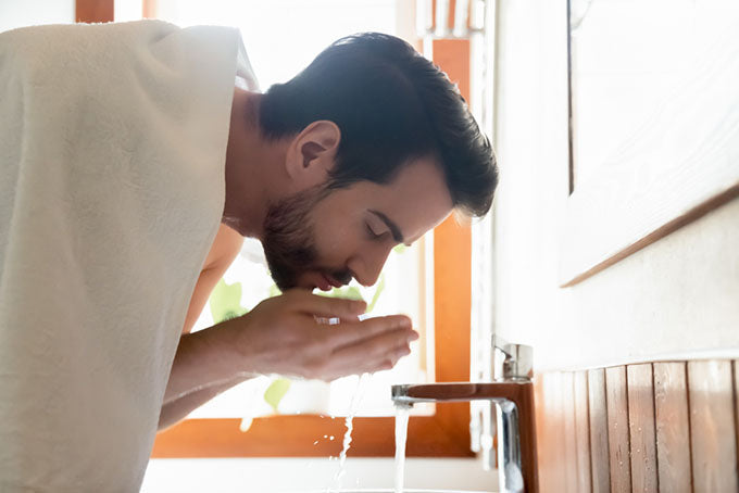 man washing face over sink