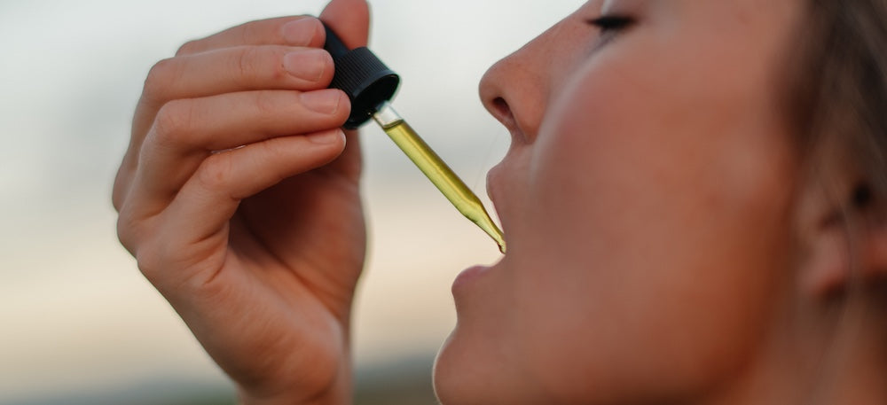 A woman using a dropper with the Life Elements Serenity Boost to help relax her cramping