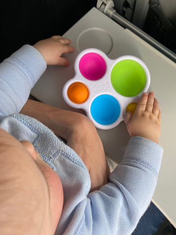 Baby playing with a Dimpl fidget toy on a plane.