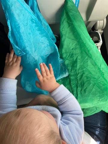 Baby playing with Sarah's Silks on a plane