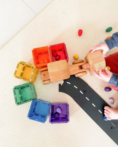 Child sorting loose parts by colour with a truck.