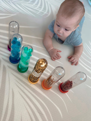 Baby enjoying tummy time with home-made sensory bottles.