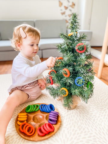 Little girl putting coloured rings onto a small Christmas tree