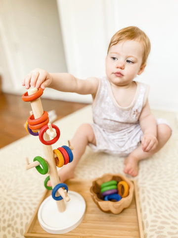 Little girl stacking rings onto a mug tree