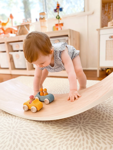 Toddler experimenting with Grimm's cars and a wobbel