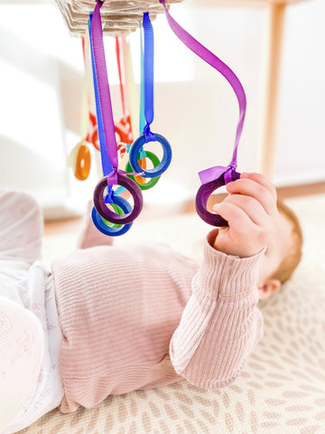 Toddler playing DIY toy using rings and ribbons