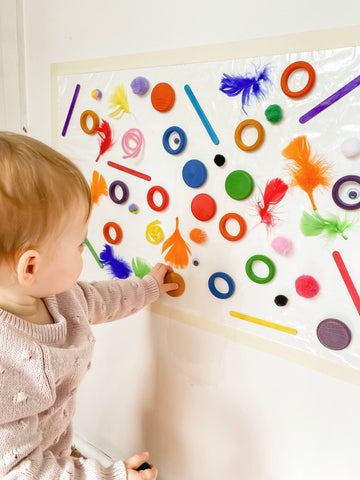 Toddler playing with a sticky wall and loose pieces