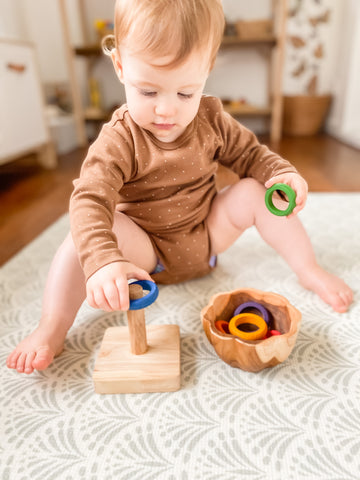 Toddler stacking Grapat rings on a toy stacker