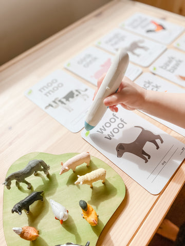 Toddler using the Chameleon Reader with flashcards and animal figurines