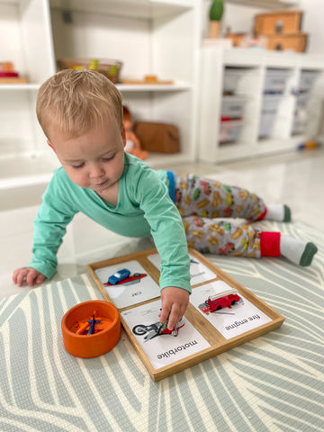 Toddler matching transport figurines with flashcards.