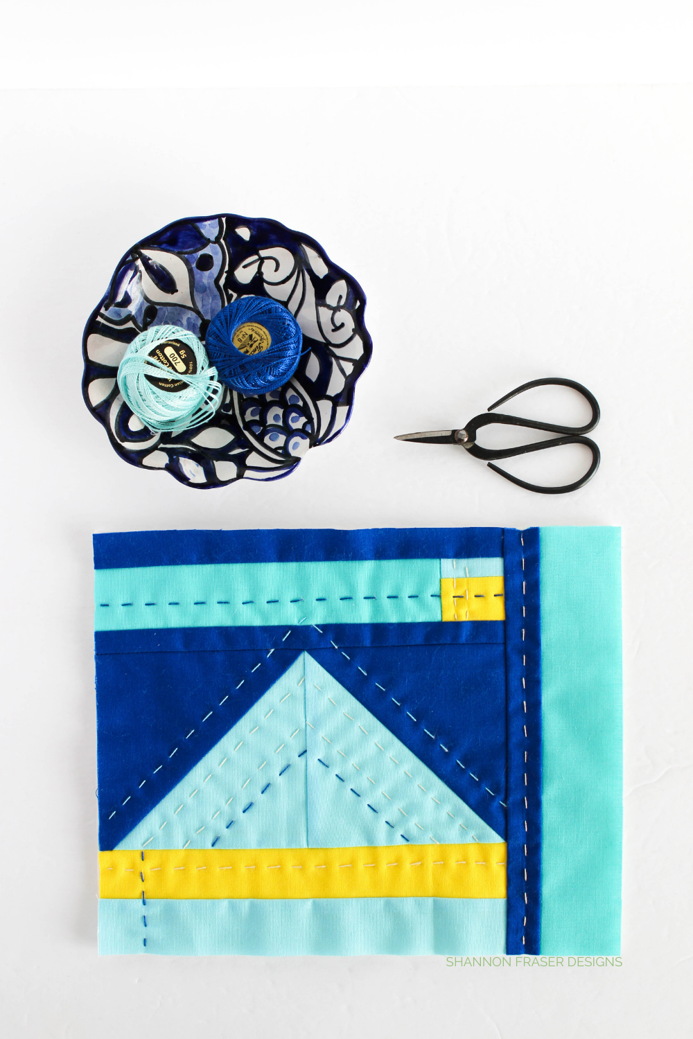 Modern mini improv quilt featuring shades of blue Kona Cotton with a pop of yellow. Hand quilted for added texture and dimension | Shannon Fraser Designs #artquilt #miniquilt