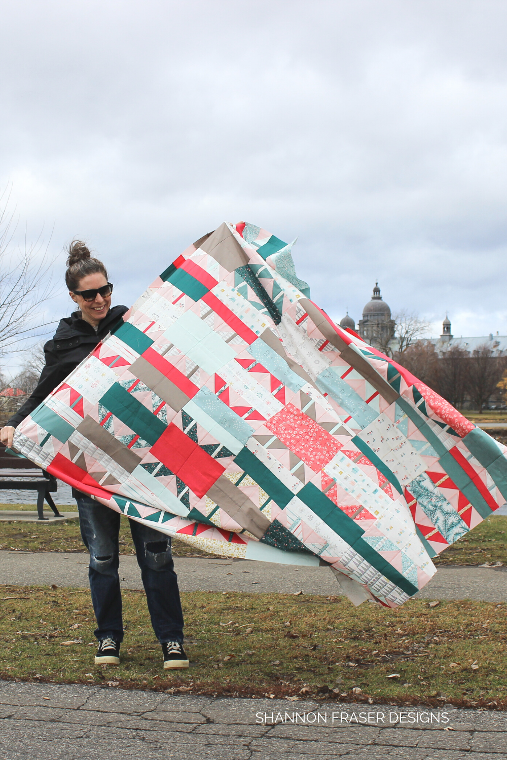 Shannon out in Montreal on a windy day holding onto the Shattered Star quilt top - the holiday version | Shattered Star Quilt Along Week 6: How to piece your quilt top | Shannon Fraser Designs #quiltsinthewild