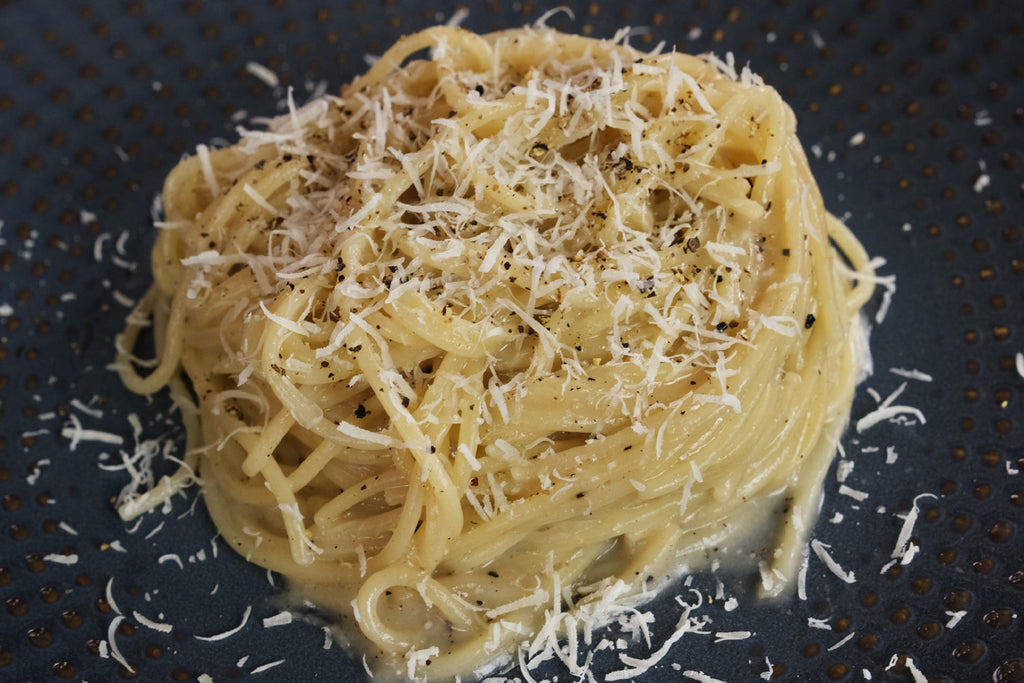 pasta cacio e pepe served with extra pecorion and pepper