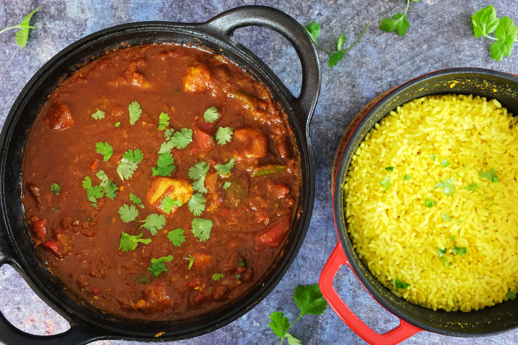 balti curry chicken in a cast iron balti dish and a dutch oven with rice