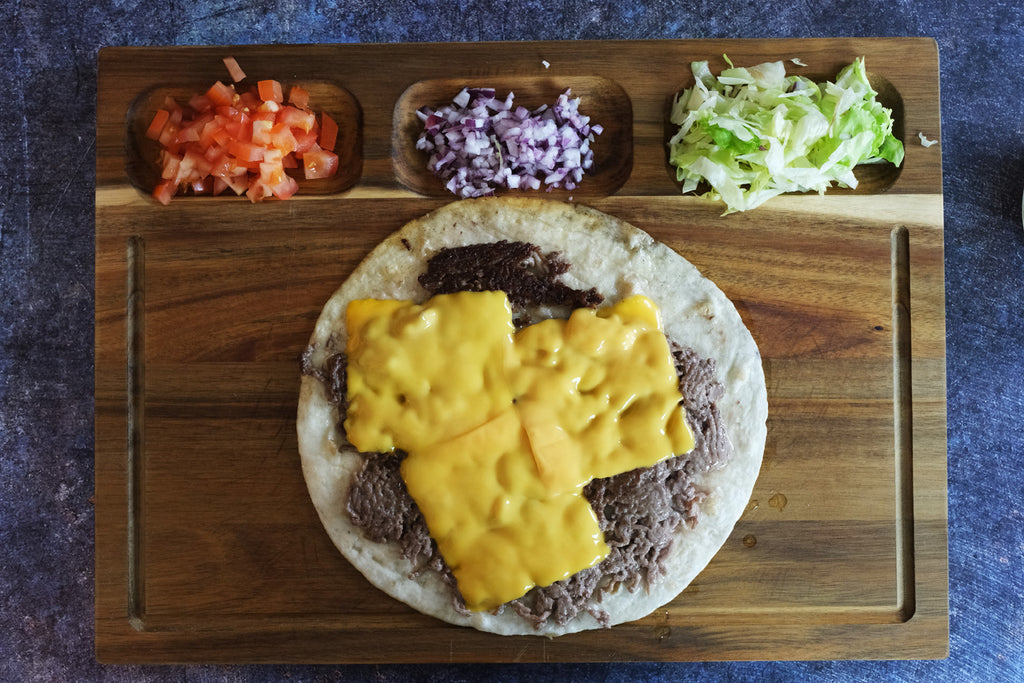 smashed taco with cheese on a wooden cutting board