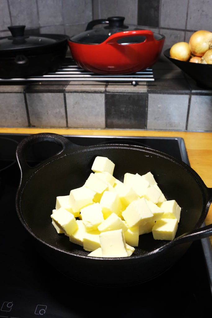 melting butter on the stove in a cast iron balti dish
