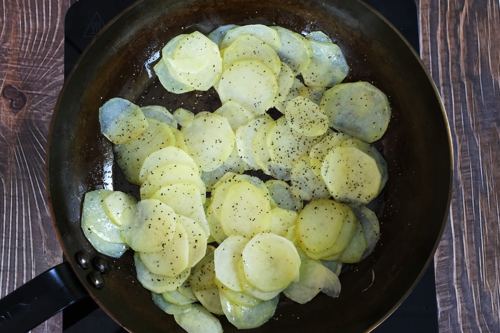 fried raw potatoes in a carbon steel pan