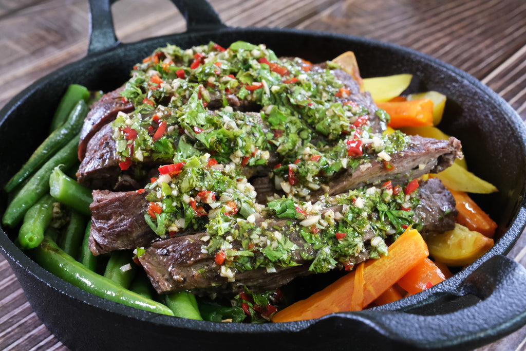 flap steak with chimichurri in a cast iron serving pan