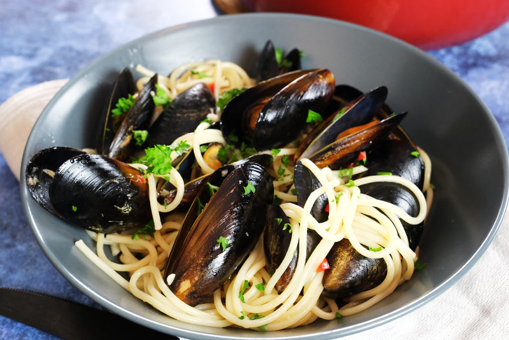 pasta vongole infront of a enameled cast iron balti dish