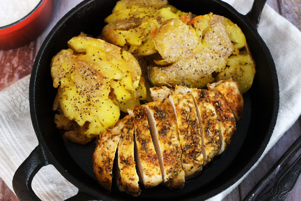 smashed potatoes and chicken in a cast iron serving pan