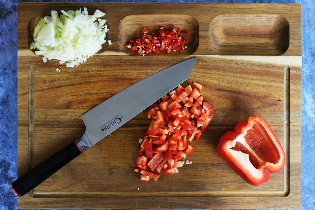 onion, chili, and bell pepper on a wooden cutting board