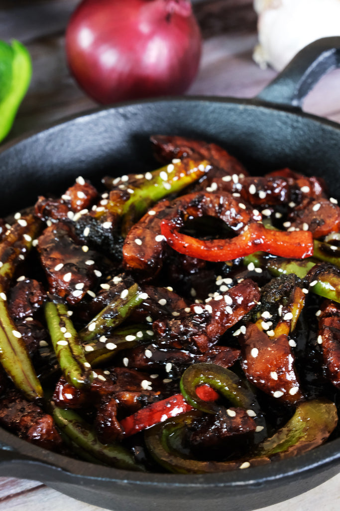 stir fry sprinkeled with sesame seeds served in a cast iron serving pan 